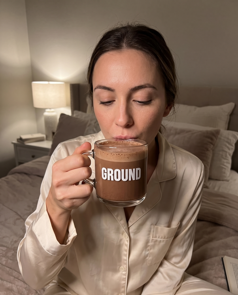 woman in pajamas drinking from a ground electrolytes for sleep glass mug